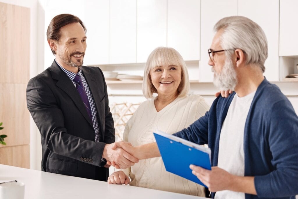 Elderly couple shaking hands with legal advisor and smiling