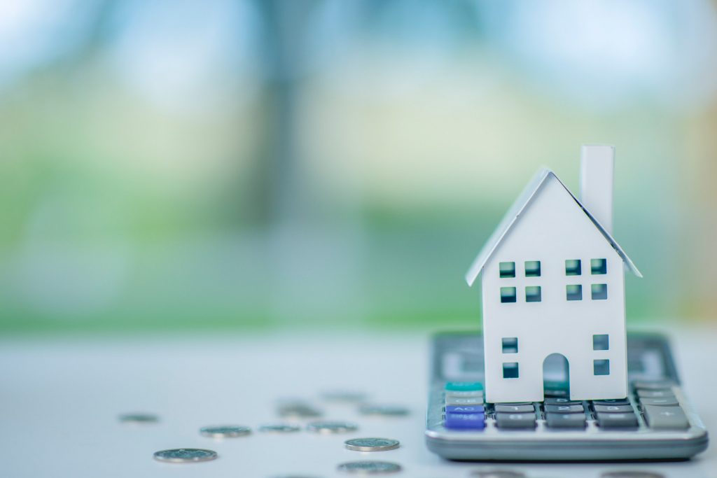 Paper house sitting on top of calculator